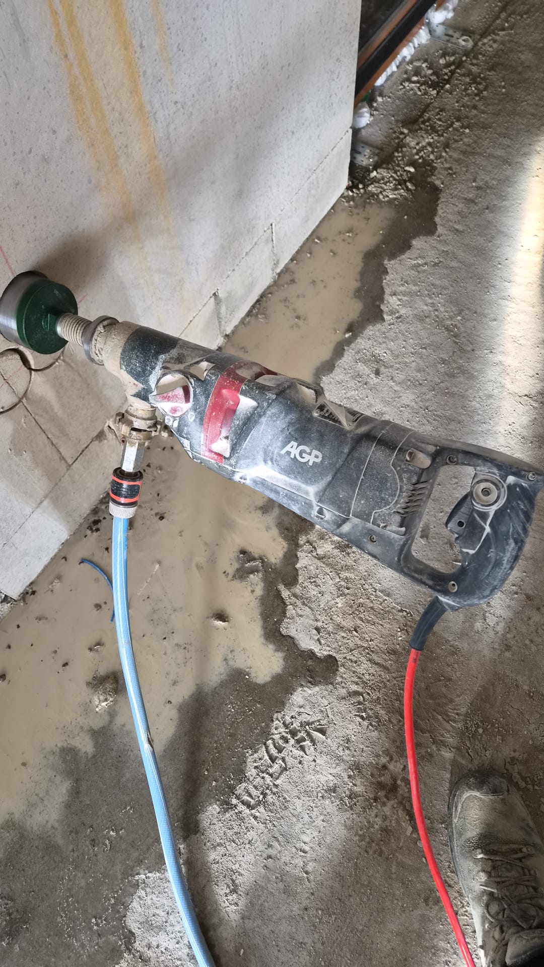 Dozenboormachine met boorkroon tegen een stenen wand